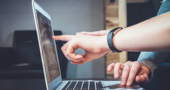 Two people pointing at a laptop using a search as a service provider.